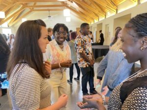 2023 Company F Trade Show A woman talks to two high school students in a college hall,